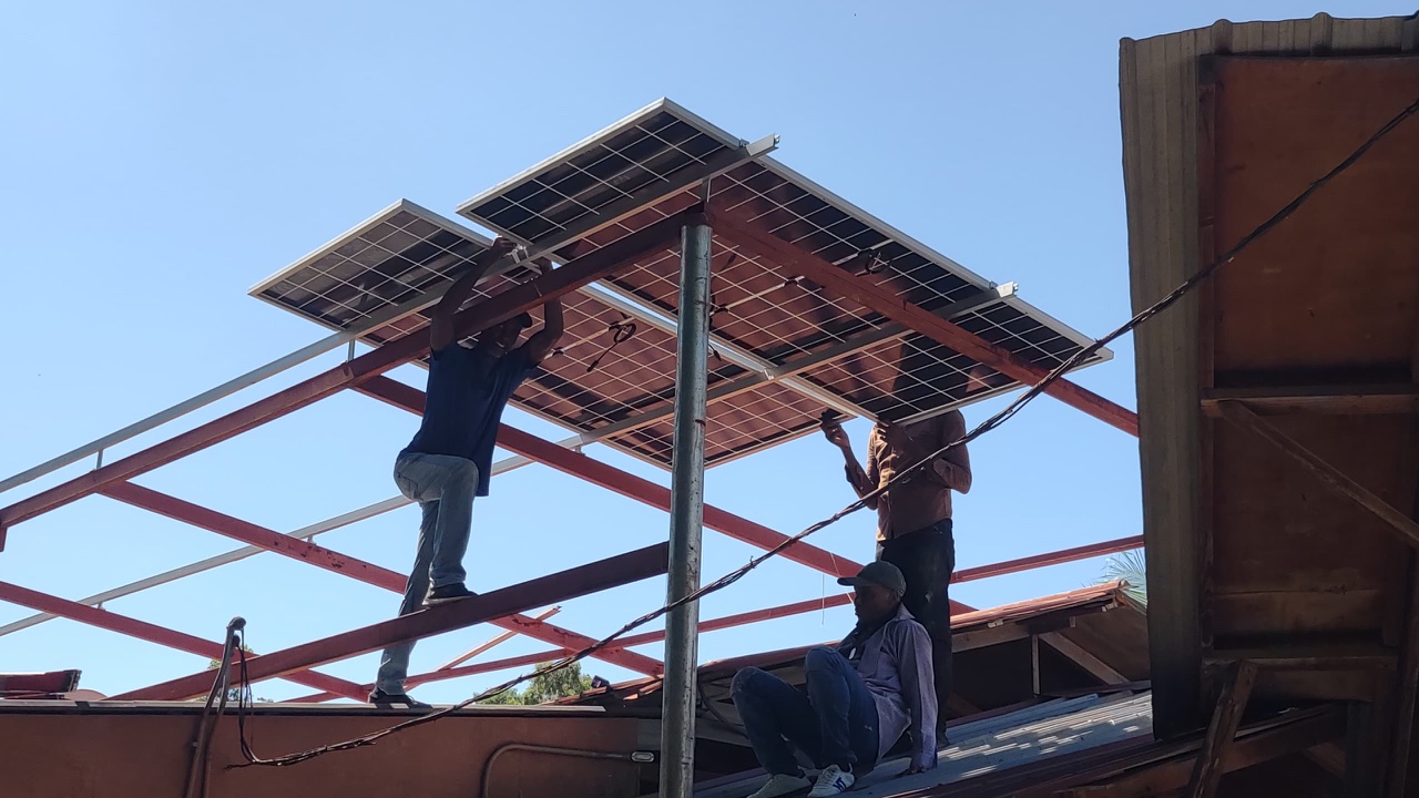 Team members installing solar panels at Hôpital Camejo.
